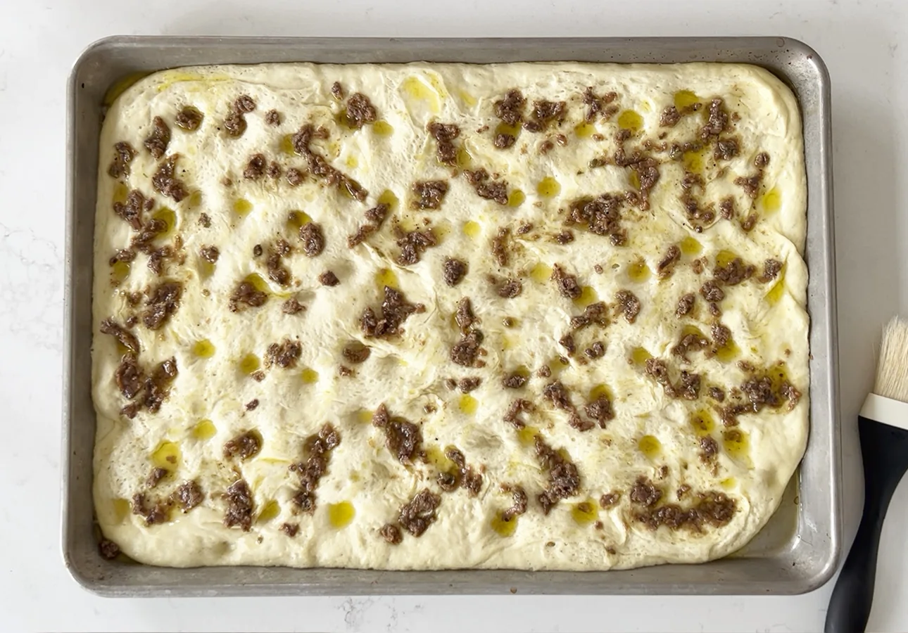 Spreading anchoïade all over the dough for making Provençal flatbread // FoodNouveau.com