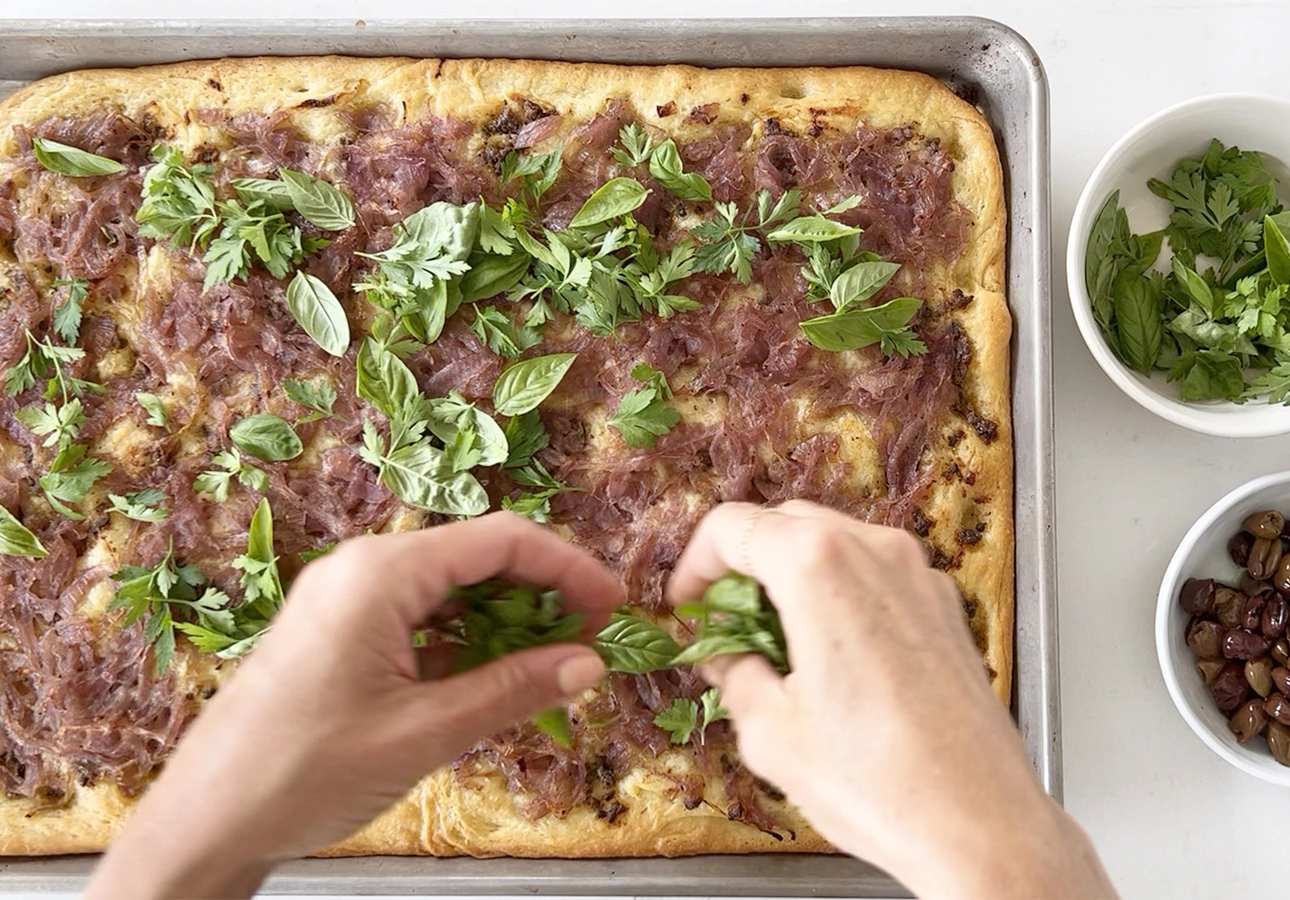 Garnishing Provençal flatbread with Niçoise olives and fresh herbs // FoodNouveau.com