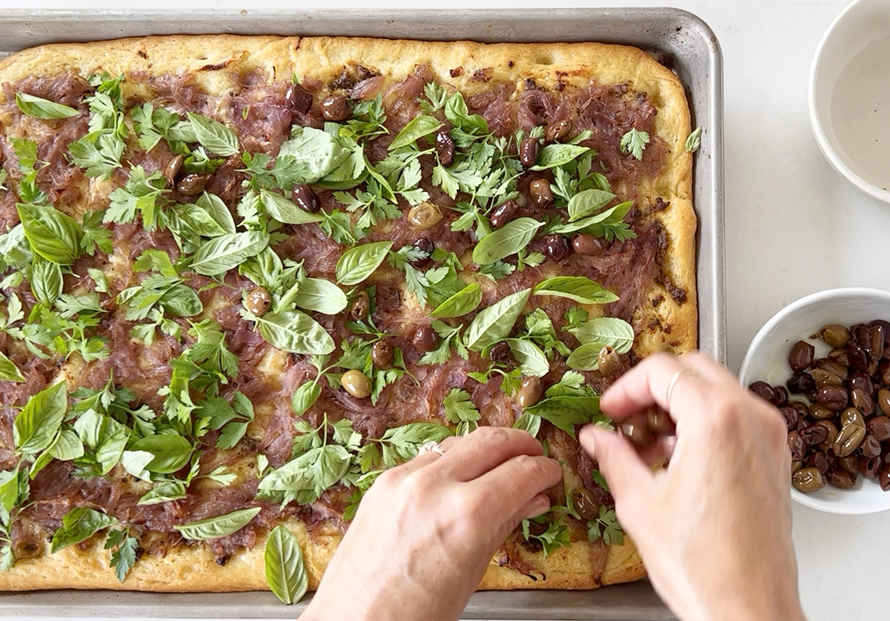 Garnishing Provençal flatbread with Niçoise olives and fresh herbs // FoodNouveau.com